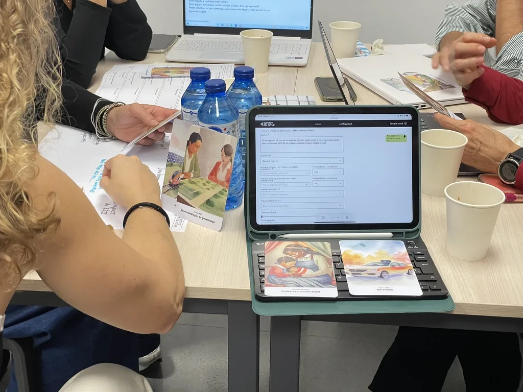 Una tauleta amb una eina digital de l’Institut, envoltada de cartes il·lustrades, durant un taller.